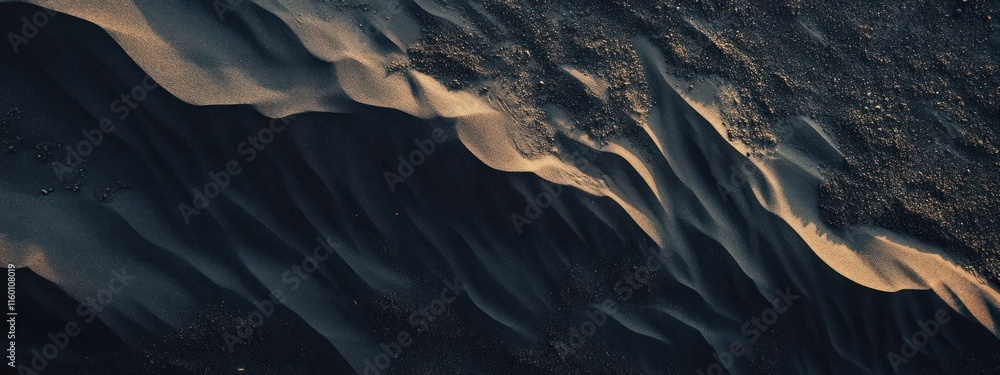 Poster Aerial view of dark sand dunes with light tan highlights, creating a textured landscape.