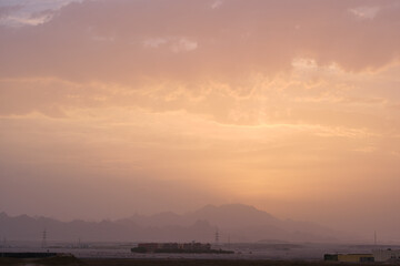 Sunset landscape with remote hotel complex against dark mountain peaks in egyptian desert