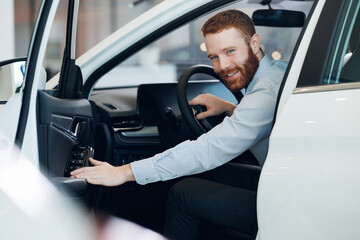 Young man in suit looking at new car and thinking about buy it. Concept making his choice.