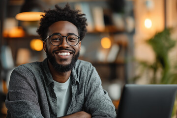 A man with glasses is smiling and sitting in front of a laptop Generative Ai.