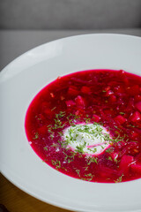 A plate with borscht, bread, garlic and lard stands on a table in a restaurant