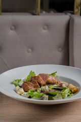Baked piece of meat among green salad and vegetables on table in restaurant