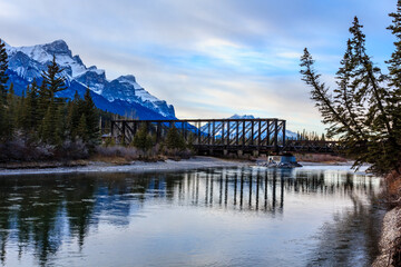 A bridge spans a river with a beautiful mountain range in the background
