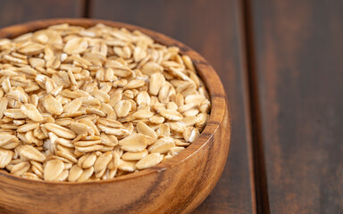 Rolled oats in a wooden bowl on a rustic wooden surface, ideal for breakfast or healthy recipes.