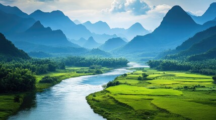 Fototapeta premium Serene river meandering through lush green countryside with majestic mountains in the background under a vibrant sky.