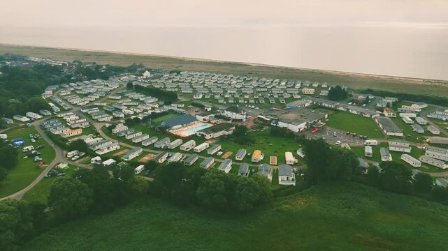 Drone view of the huts of Lowestoft Beach with green field, and sea in the background in England