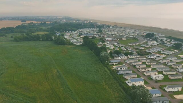 Drone view of stunning coastal landscape, featuring the huts of Lowestoft Beach with green field