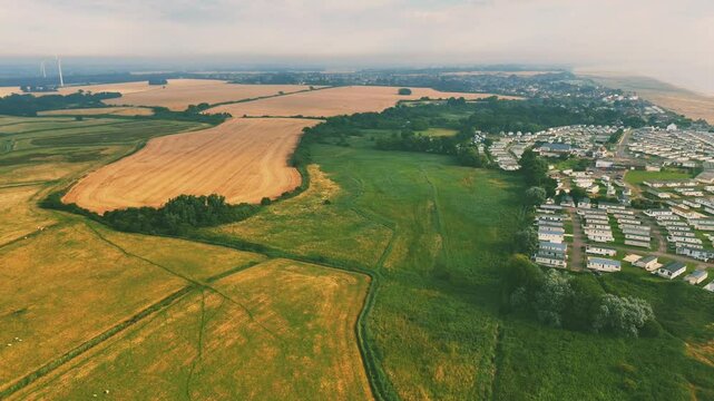 Drone view of stunning coastal landscape, featuring the huts of Lowestoft Beach with green fields