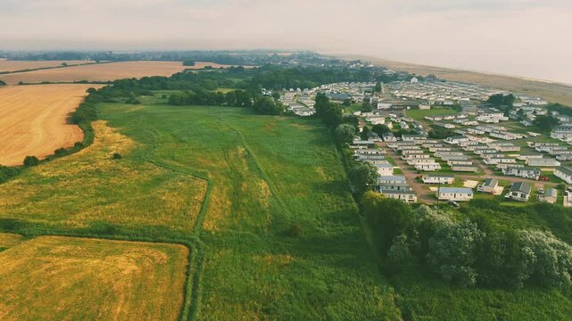 Drone view of stunning coastal landscape, featuring the huts of Lowestoft Beach with green fields