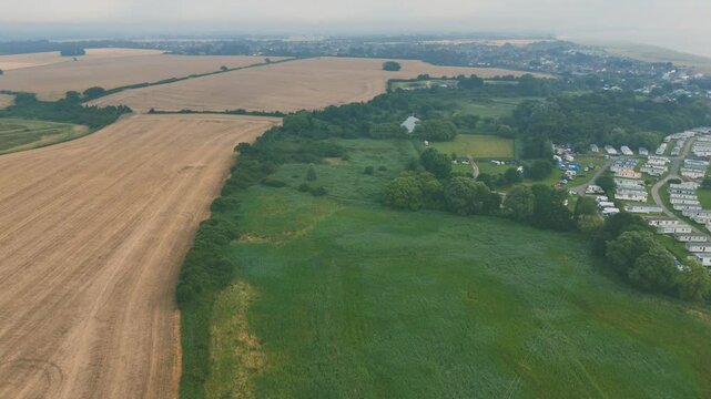 Drone view of stunning coastal landscape, featuring the huts of Lowestoft Beach with green fields