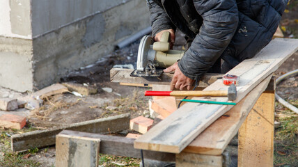 A man is using a saw to cut a piece of wood