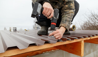 A man is working on a roof with a power drill