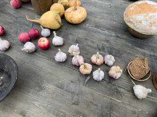 A table with a variety of vegetables and fruits, including garlic, apples