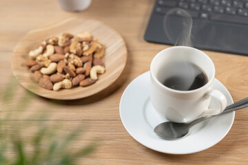 湯気の立つ暖かなコーヒーとミックスナッツ