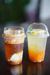 Close up glass of ice iced cool yuzu espresso, iced emaricano with coconut water on wooden table of a coffee shop summer terrace, menu photography.