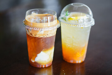 Close up glass of ice iced cool yuzu espresso, iced emaricano with coconut water on wooden table of a coffee shop summer terrace, menu photography.
