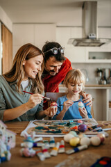 Family teamwork as they dip Easter eggs into dye and add colorful patterns