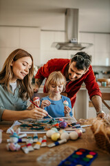 Family teamwork as they dip Easter eggs into dye and add colorful patterns