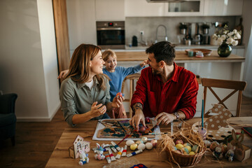 Fototapeta premium Family painting Easter eggs while surrounded by festive decor.