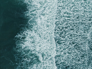 Aerial view, top view of sea waves on beach sand. Royalty high-quality free best stock of turquoise colored breaking wave seascape on the beach. Wave crashing, splash