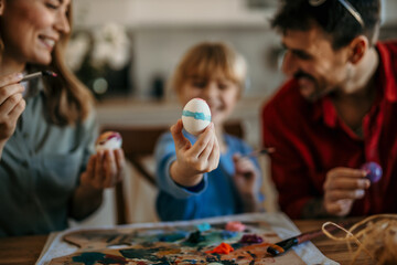 Fototapeta premium Mom, dad, and daughter collaborating to create beautiful Easter egg designs at home