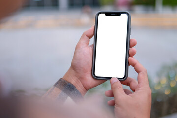 A young man is holding a phone with a white screen in his hand.
