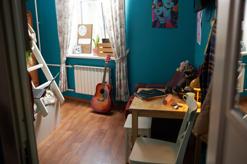 No people shot of modern girls dorm room interior with blue walls, decorated with colorful posters,...