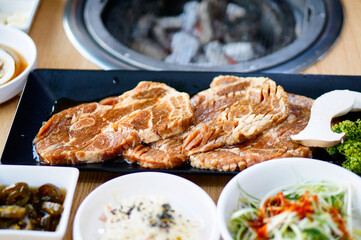 식탁 위에 돼지 양념 갈비를 굽기 위에 놓여 있는 모습