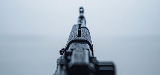 A gun is shown with a wet grip. Concept of danger and unease, as the gun is pointed at the camera. The wet grip suggests that the person holding the gun may be nervous or anxious