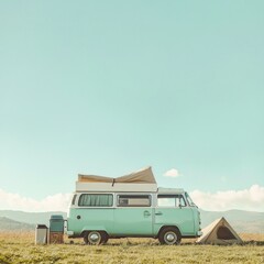 Pastel green vintage camper van parked in a grassy field with a tent, under a clear sky.