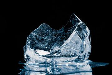 Melting piece of ice on a black background with reflection.