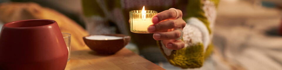 Gen Z girl creating cozy and warm atmosphere in dorm room, lighting up scented candles, website...