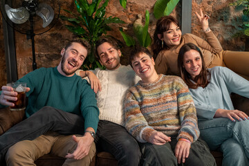 Happy group of friends relaxing on a couch at cozy cafe