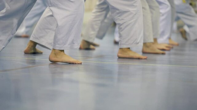 Karate class practicing coordinated stances in white uniforms
