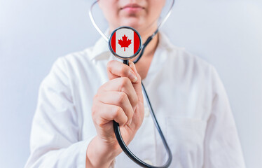 Female doctor holding stethoscope with Canada flag. National Health System of Canada