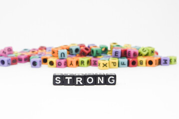 Image of alphabet cube beads forming the word STRONG for learning to spell and as a background for motivational words.