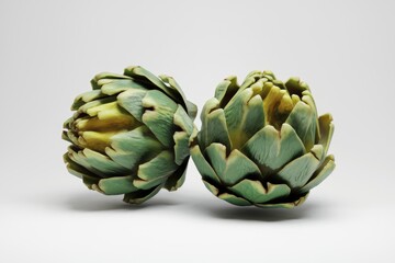 Fototapeta premium Two vibrant green artichokes, ready to be cooked or enjoyed raw, showcasing their intricate textures and unique shapes.