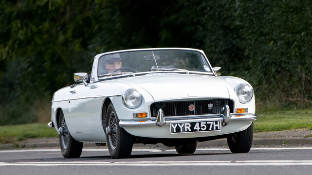1970 white MGB classic car driving on an English country road.