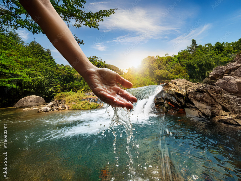 Poster a hand reaches out to catch the cascading water of a small waterfall in a lush green forest. sunligh