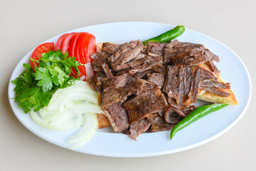 Turkish  Traditional Ramadan doner kebab with tasty tomato sauce and rice or turkish pilav in white plate on table background. Lavash doner kebab ( doner zurna durum )  Pilavustu Doner Iskender kebap