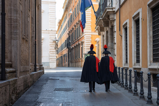 Carabinieri in ceremonial uniforms walking through a historic Roman street