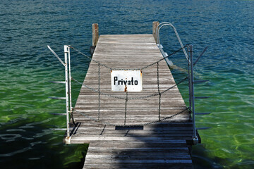 Wooden Jetty with 'Private' Sign on Deserted Beach beside Waters of Lake Garda 