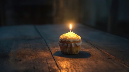 Charming cupcake with a single candle glowing softly on a wooden table