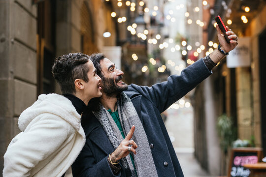 Gay couple taking selfie in city with christmas lights