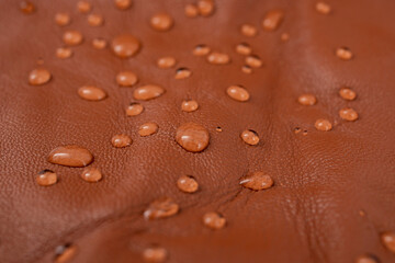 Round water drops on red brown leather texture, top view, soft focus close up abstract pattern