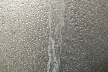 Limescale trails from hard water issue and water drops, on metallic gray  plastic shower wall,...