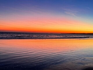 Obraz premium featuring a view of the beach at sunset, with the sky adorned with beautiful color gradations, ranging from dark blue to bright orange.