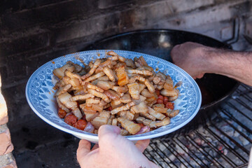 Preparing La Mancha or Castilian migas as a family where everyone eats with a spoon from the same pot. we can appreciate all its ingredients, chistorra, bacon, bread, pepper...