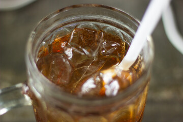 A glass filled with iced tea, clear ice cubes, and a white straw for drinking