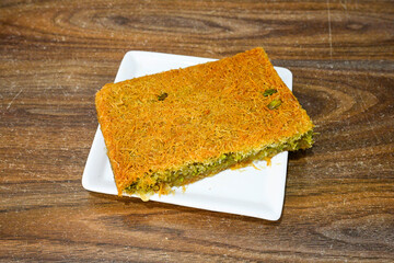 Pistachio kadayif on a plate. Turkish Dessert Kadayif with pistachio powder. Local name burma kadayif, antep fistikli, cevizli kadayif .